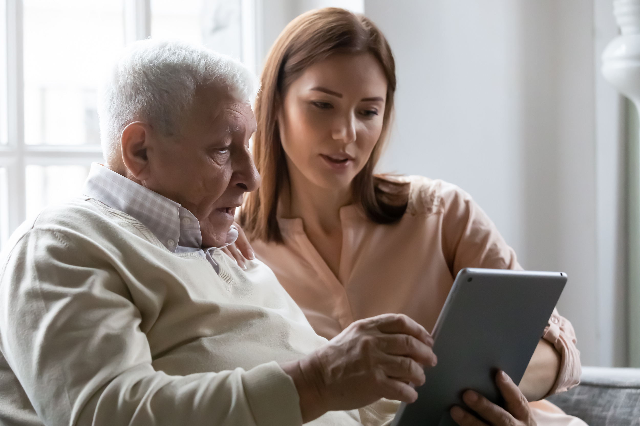 A caregiver helping an older man with a tablet