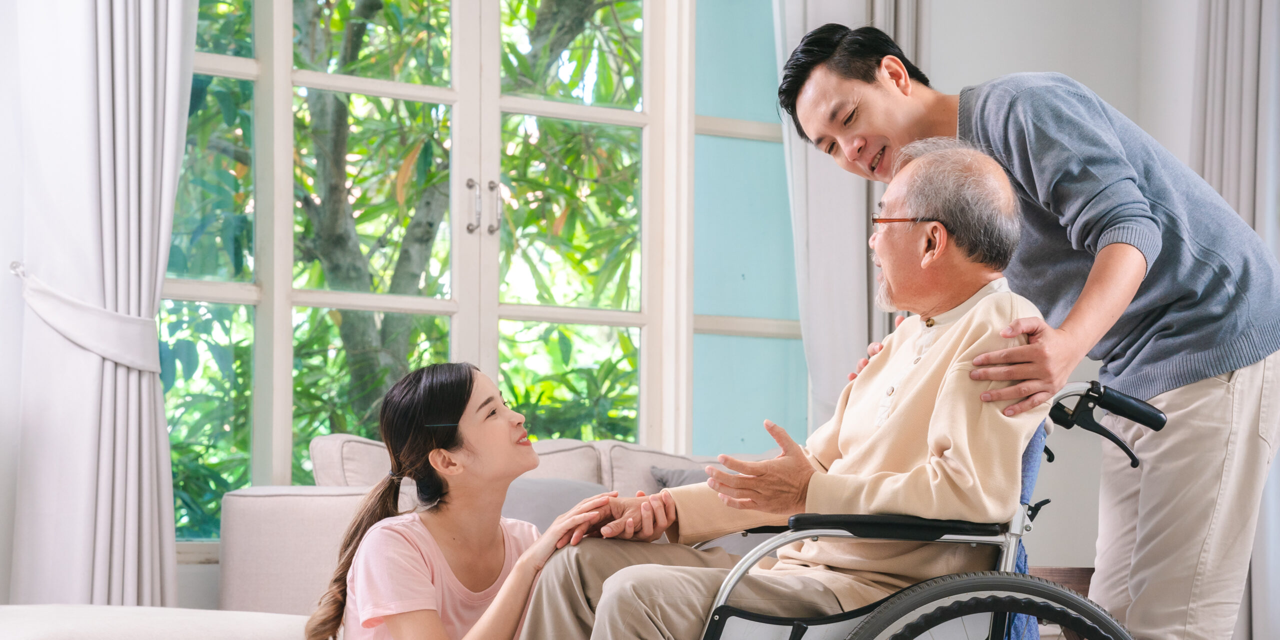 Gentle daughter and son are taking care and support help their retired and elderly father or dad on wheelchair at home, positive energy for senior patient, bonding between family, disability caregiver