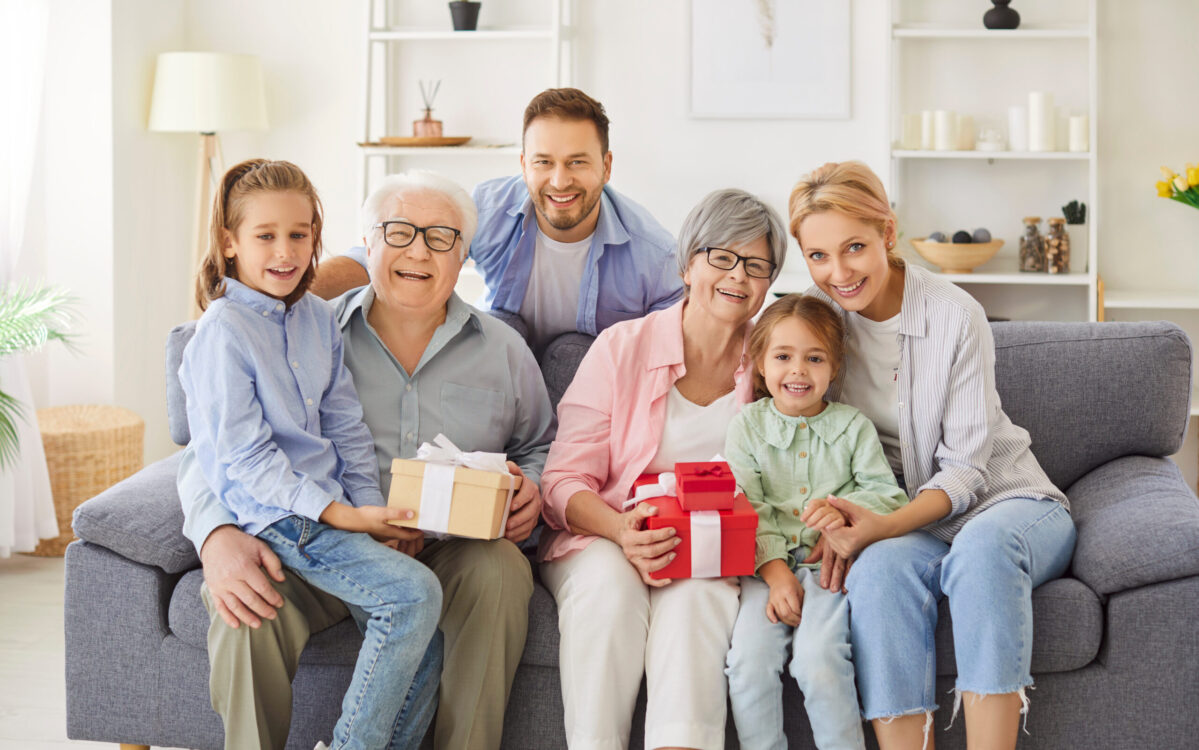 Happy family portrait, three generation people, grandparents, old granny holding birthday present